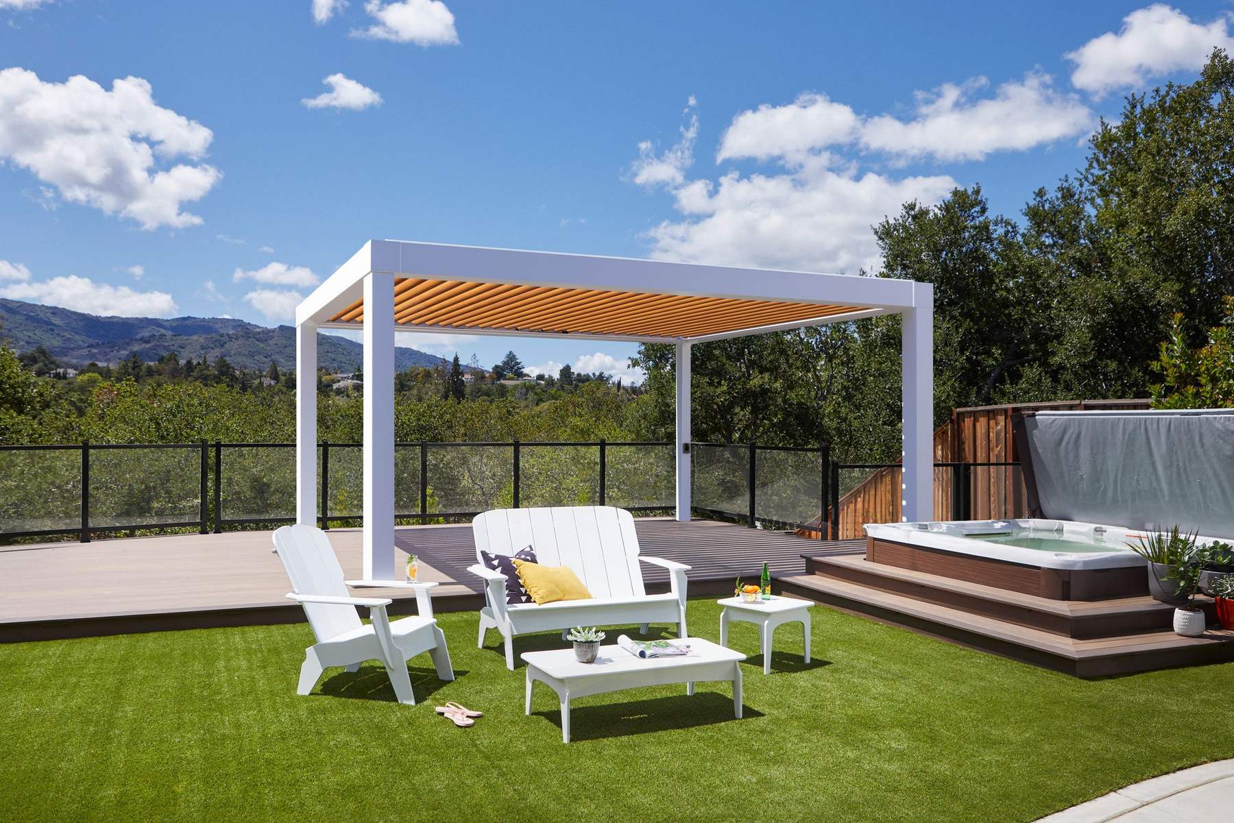 A louvered pergola over a composite deck at the edge of a lawn
